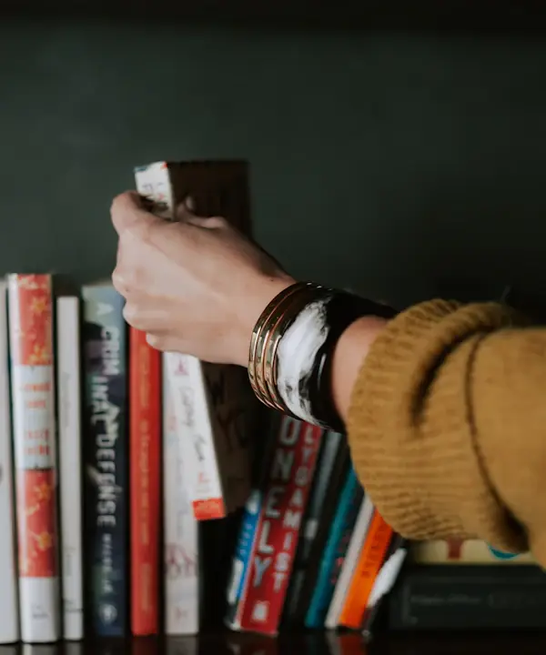 A reader taking a book down from a shelf