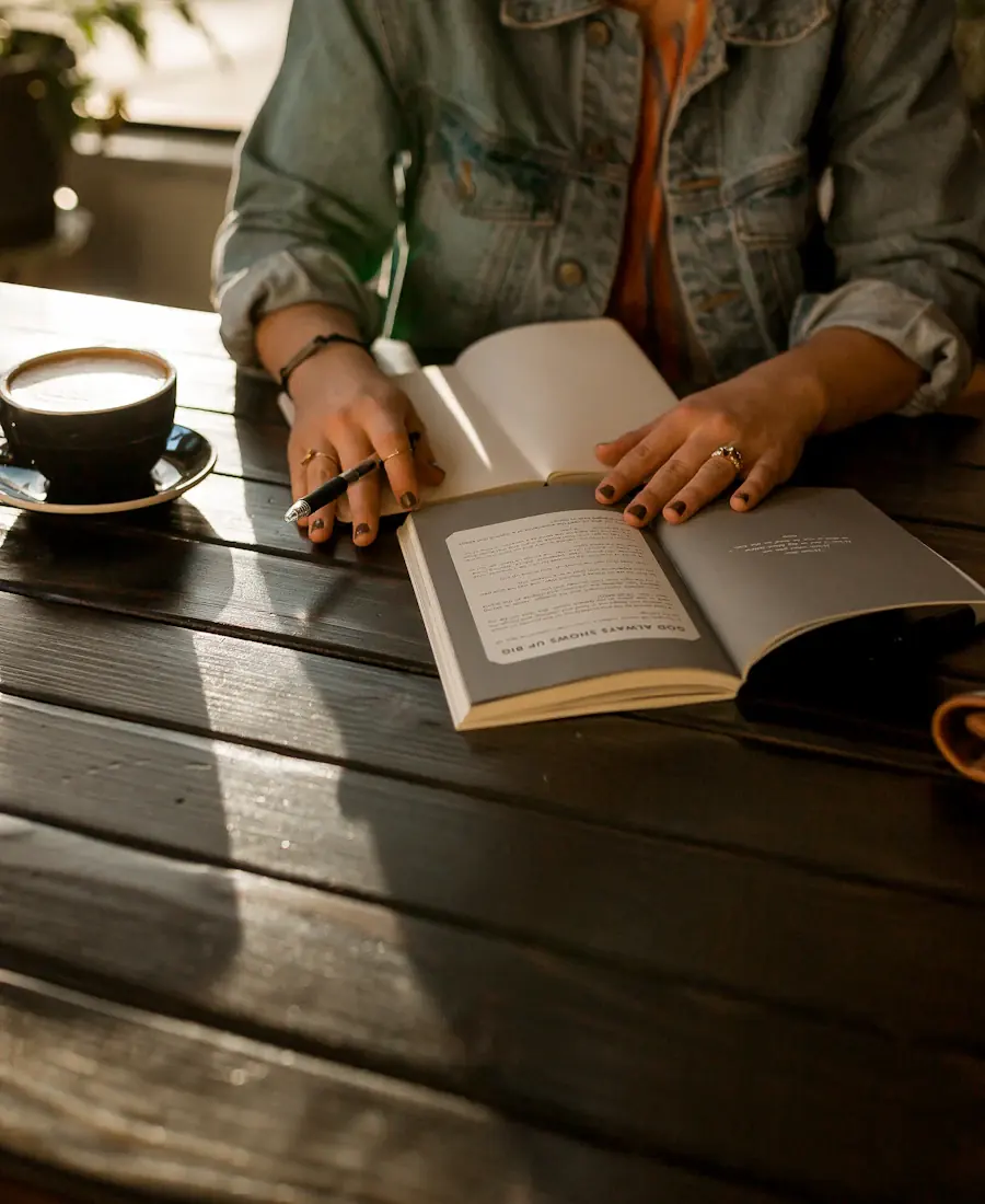 An author reading at a wooden table beside a cup of coffee